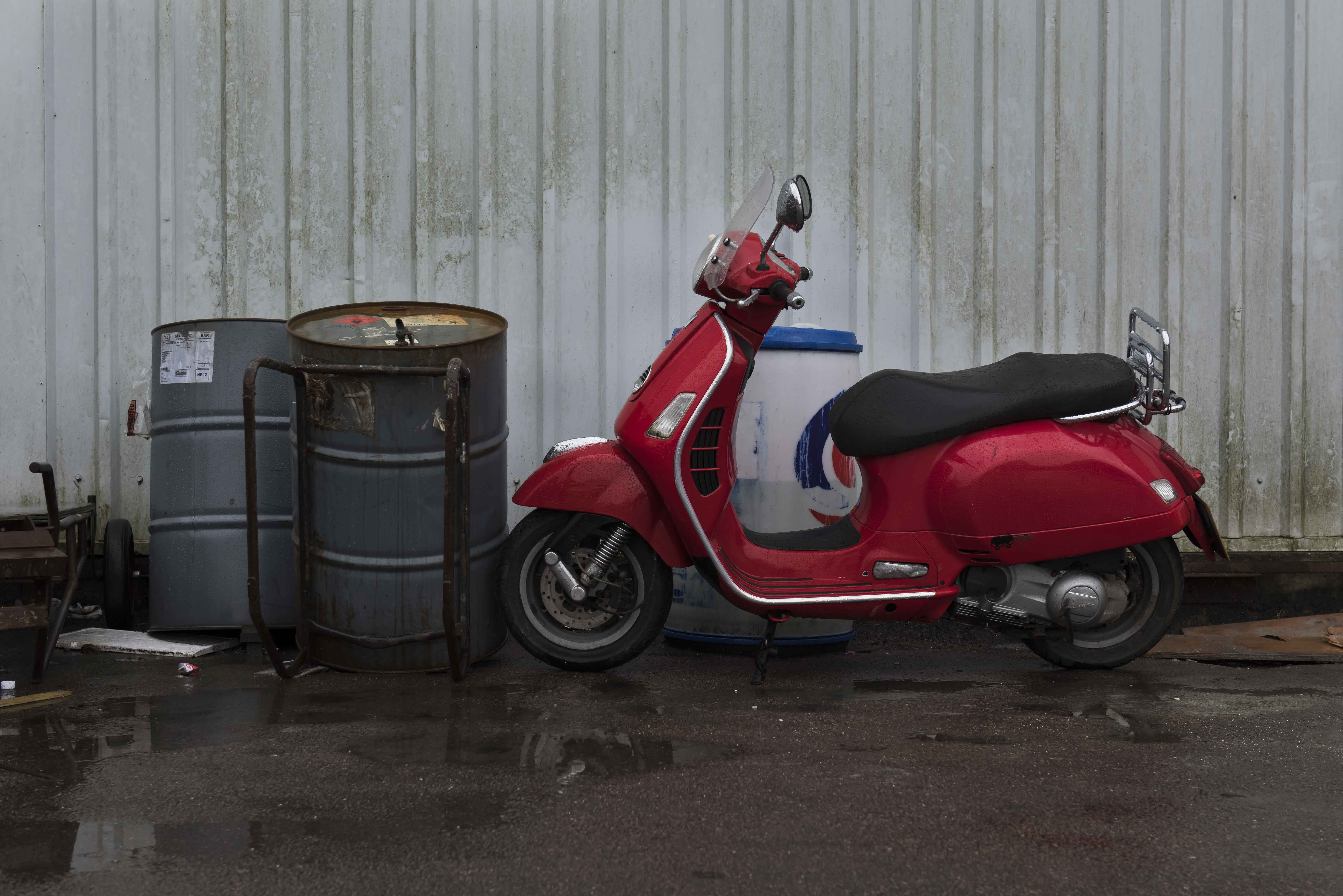 Red Vespa scooter and oil drums