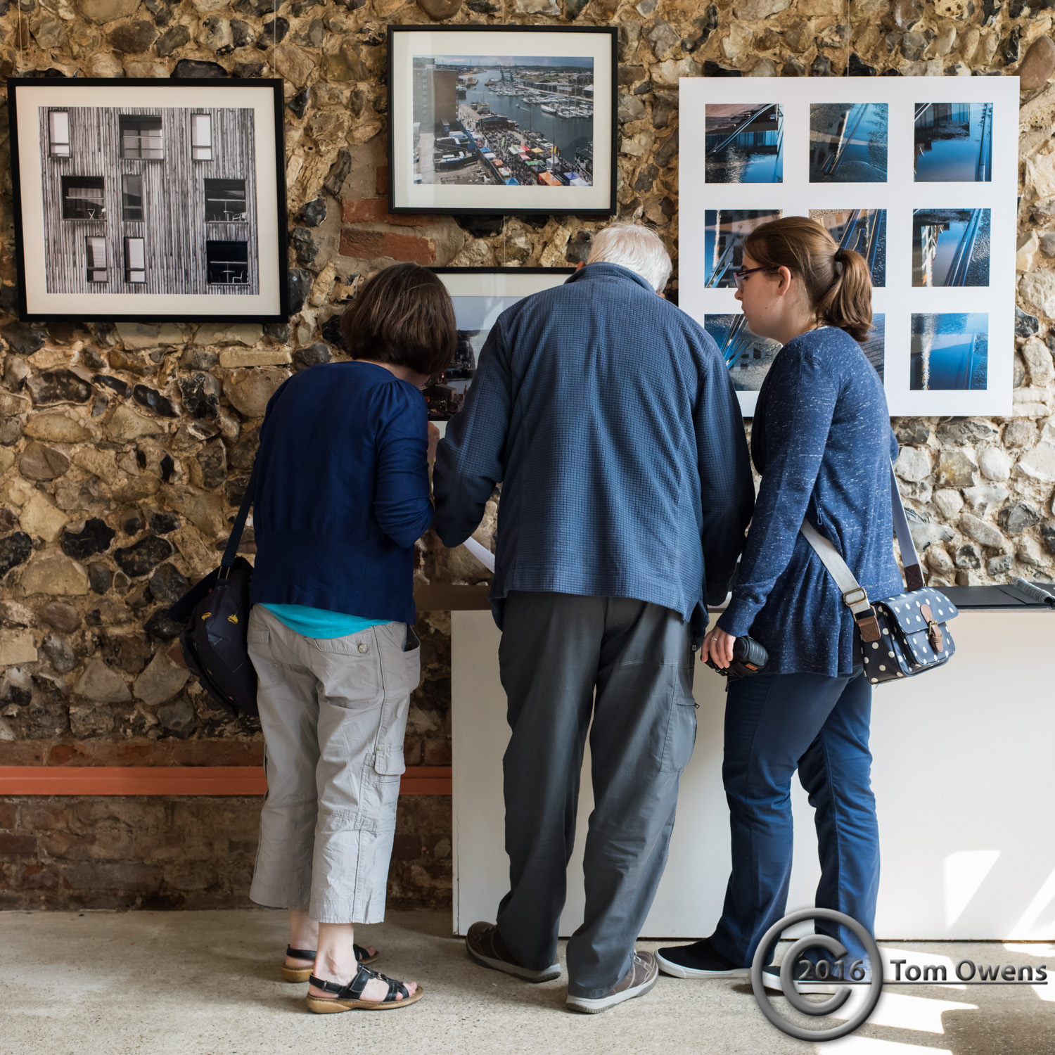 Two women and a man looking through books at gallery
