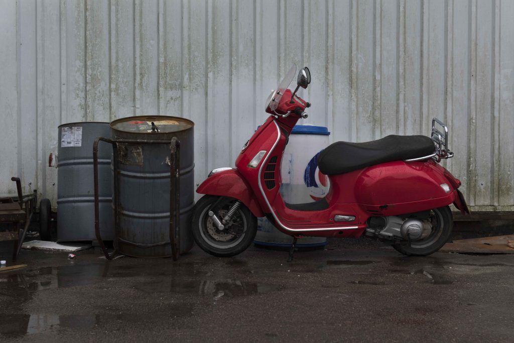 Red Vespa scooter and oil drums